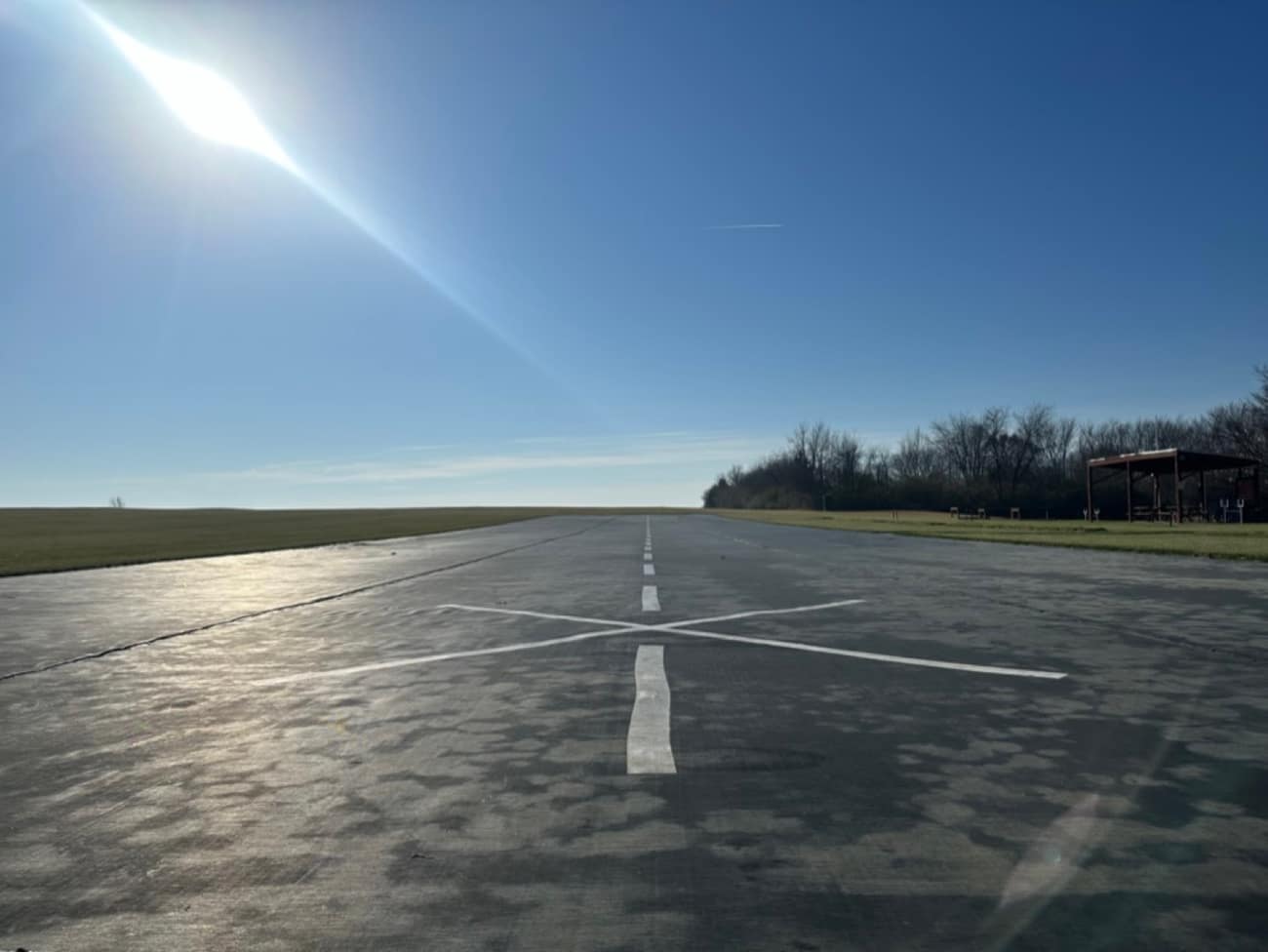 Sunlit view down the runway centerline, with the club pavilion in the distance