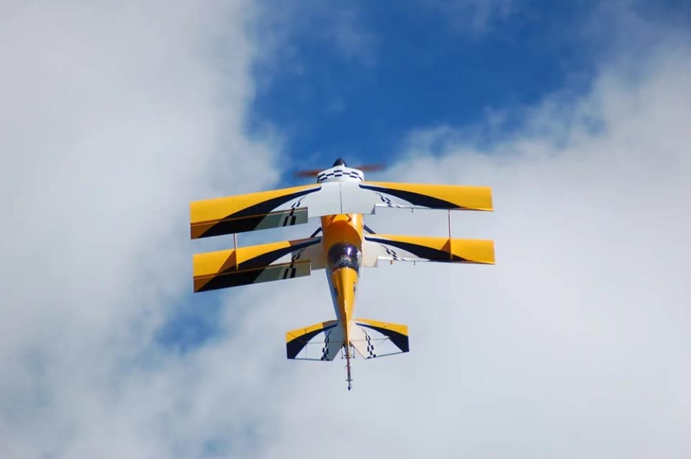 An RC biplane climbing head-on into the clouds