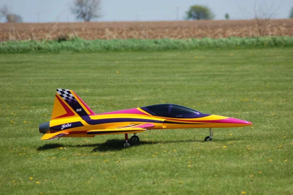 A yellow and pink RC turbine jet parked on the grass