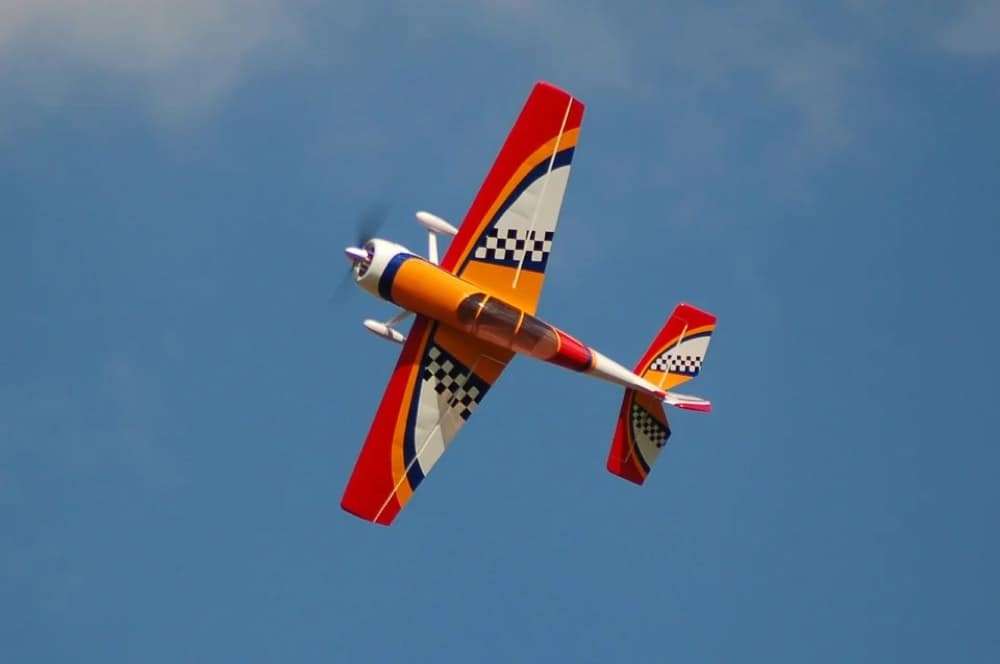 A colorful aerobatic RC plane banking in flight
